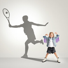 Fototapeta na wymiar Childhood and dream about big and famous future. Conceptual image with girl and shadow of female tennis player on light gray background.