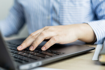 Hands of businesswoman typing on a laptop keyboard, she is using a messaging program to talk to a business partner who is opening a startup company. Concept of using technology in communication.