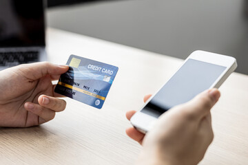 A woman holding a cell phone and credit card, she fills in her credit card information in a mobile shopping app to pay for the purchase. Online shopping concept using credit card payments.