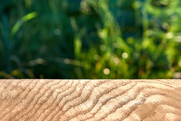 Wooden texture, smooth oak surface, grass in the background out of focus.
