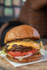 Classic cheeseburger with beef burger, pickle, cheese, tomato, onion, lettuce and ketchup mustard on blurred background.