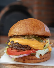 Classic cheeseburger with beef burger, pickle, cheese, tomato, onion, lettuce and ketchup mustard on blurred background.