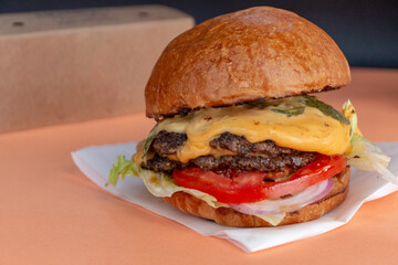 Classic cheeseburger with beef burger, pickle, cheese, tomato, onion, lettuce and ketchup mustard on blurred background and travel packaging.