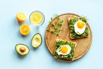 Breakfast with avocado toasts and fried eggs, top view