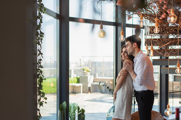 Fototapeta premium man in shirt hugging smiling woman in slip dress in restaurant