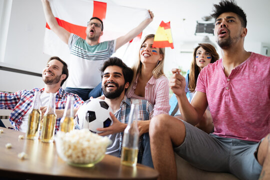 Cheerful and happy group of friends watching olympic games on tv.