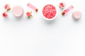 Cosmetics with rose oil essence. Face cream lotion and flowers, top view