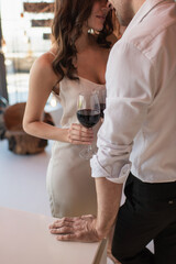 cropped view of couple standing and holding glasses of red wine