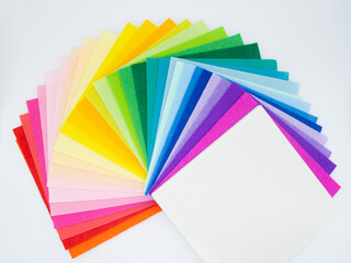 The square pieces of felt spread out by a color spectrum on similarity of a rainbow: from shades of red, pink, yellow, green, blue and bright violette at the end. White background. Copy space
