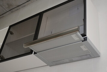 Fototapeta premium A close-up of an integrated into cupboard telescopic cooker hood, built-in kitchen extractor hood on a black and white kitchen.