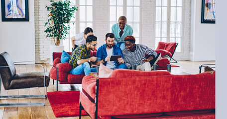 Group of diverse people watching live stream of match on modern digital talet waiting for online...