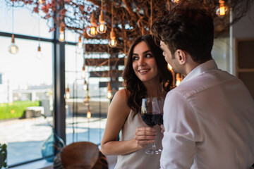 smiling man and woman holding glasses of red wine in restaurant