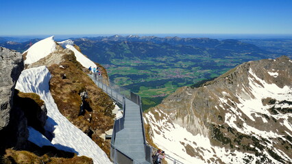 Blick vom Gipfel des Nebelhorns hinunter nach Oberstdorf und auf Aussichtssteg mit Menschen