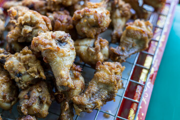 Plenty of pieces of chicken drumsticks are piled up on the grill.