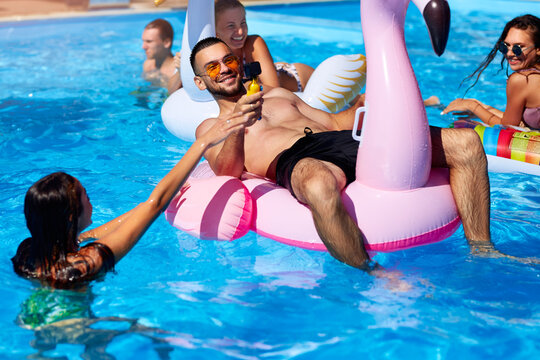 Travel blogger man taking selfie photo with action camera in a swimming pool. Lifestyle vlogger films vlog from luxury resort on sunny day. Fitted guy live streaming for social media likes. - Powered by Adobe