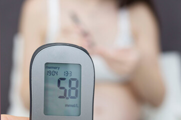 Diabetes of pregnant women. A pregnant woman with a stomach measures the level of glucose in the blood with a glucometer.