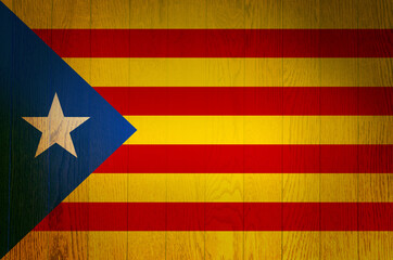 The flag of Catalonia on a grunge wooden background.