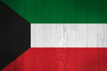 The flag of Kuwait on a grunge wooden background.
