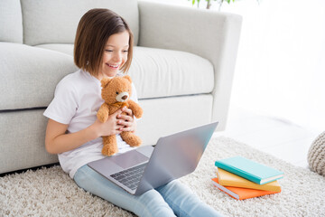 Profile side photo of young cheerful little girl happy positive smile speak talk video call laptop show teddy bear indoors
