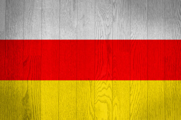 The flag of South Ossetia on a grunge wooden background.