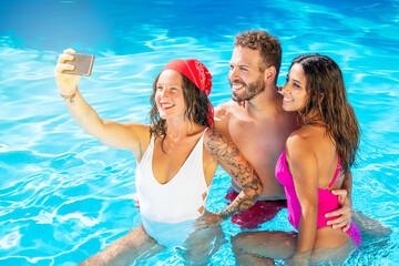 Group of friends together in the swimming pool taking selfie
