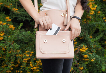 Stylish woman putting the credit card in the handbag.