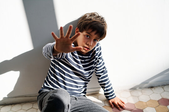 Scared kid with stop gesture suffering from domestic violence