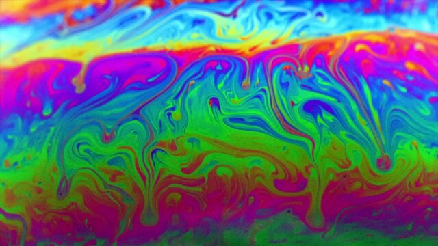 Vivid rainbow colours of a Macro soap bubbles creating psychedelic swirling rainbow patterns under light dome
