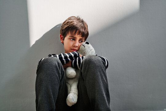 Sad boy with toy sitting on floor