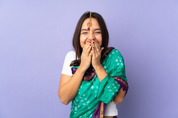 Young Indian woman isolated on purple background happy and smiling covering mouth with hands