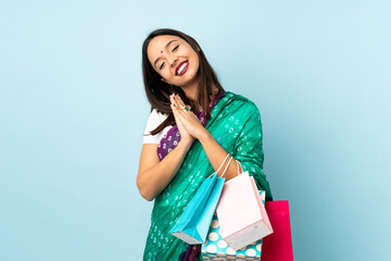 Young Indian woman with shopping bags keeps palm together. Person asks for something