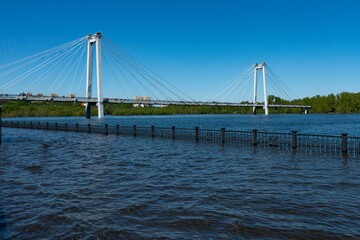 Flooded embankment with a large suspended bridge in the background.