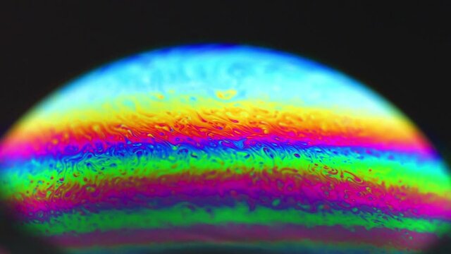 Vivid rainbow colours of a Macro soap bubbles creating psychedelic swirling rainbow patterns under light dome