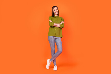 Fototapeta na wymiar Full length photo of nice brunette millennial lady crossed arms wear shirt jeans isolated on orange color background