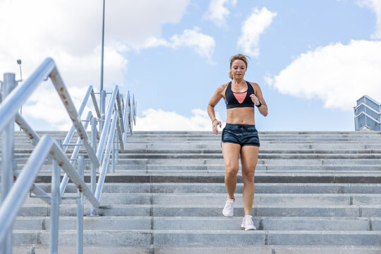 Young woman running while going down the stairs
