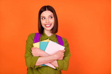 Obraz premium Photo of smart brunette lady hug books look empty space wear bag shirt isolated on orange color background