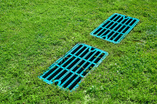 manhole drainage grates on the lawn with green grass septic tank cover, sump cesspool drainage system environment design side view with copy space, nobody.