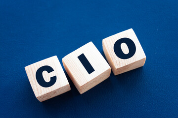 CIO written on wooden cubes - arranged in a vertical pyramid, grey and blue background, CIO - short for Chief Information Investment Officer, business concept