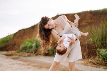 Mother with a child have fun outdoors playing games love each other. Young family with little baby boy spending time together on the beach. Family, childhood, active lifestyle concept.
