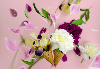 Summer composition of peony and iris flowers in a waffle cup for ice cream. Summer flower background