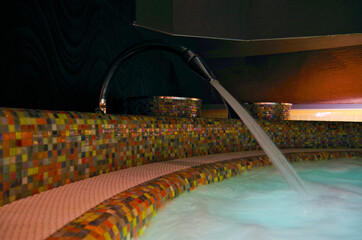Water fountain for back massage inside whirlpool with mosaic tiles in thermal suite spa wellness...