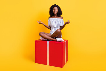 Portrait of attractive dreamy girl sitting on big large box meditating inspiration isolated over bright yellow color background