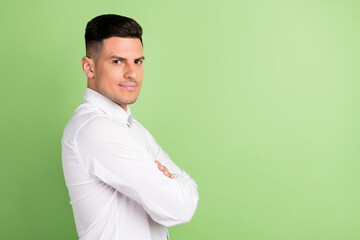 Photo of sweet confident young gentleman wear white shirt smiling arms folded empty space isolated green color background