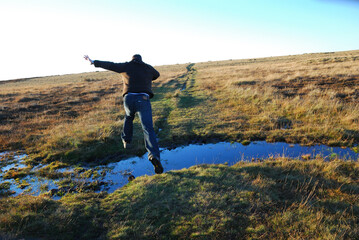 Man jumping across the water at North York Moors National Park