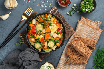 Vegetable stew, rye bread and greens on a gray-blue background.