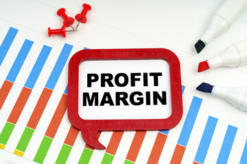 There are markers, charts and a sign on the table - PROFIT MARGIN