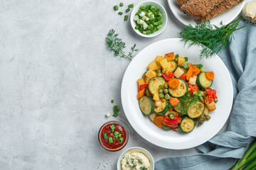 Healthy stewed vegetables in a white plate on a gray background.
