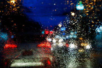 Drops Of Rain Drizzle on the glass windshield in the evening. street in the heavy rain. Bokeh Tail light. soft Focus. Please drive carefully, slippery road. soft focus.