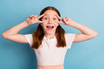 Photo of funny carefree person fingers show v-sign near eyes open mouth isolated on blue color background