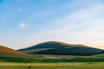 Fototapeta premium Beautiful summer landscape. The green hills, forest and mountains at the sunrise. Nature wallpaper